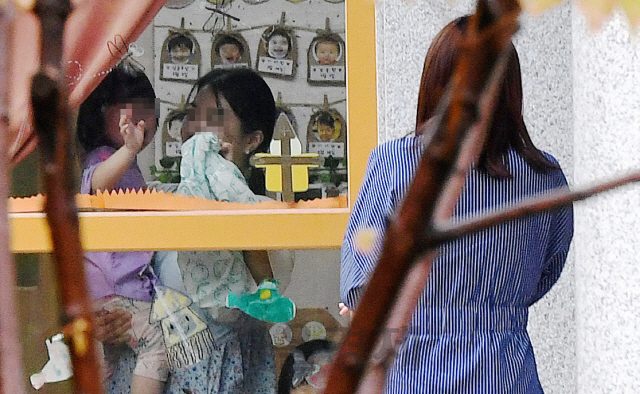 한 아이 엄마가 여의도 국회의사당 직장내 보육시설인  어린이집에서 울고 있는 아이를 보면서 발길을 돌리고 있다./ 이호재 기자