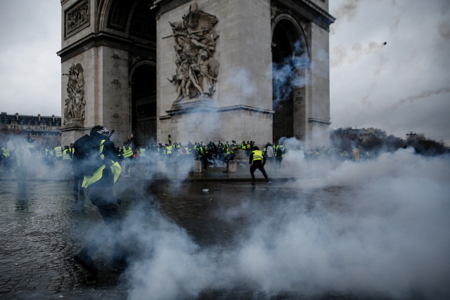 프랑스 파리의 개선문 주위에서 지난 1일(현지시간) ‘노란 조끼’ 시위대가 최루가스를 터뜨리며 진압에 나선 경찰과 충돌하고 있다. /연합뉴스