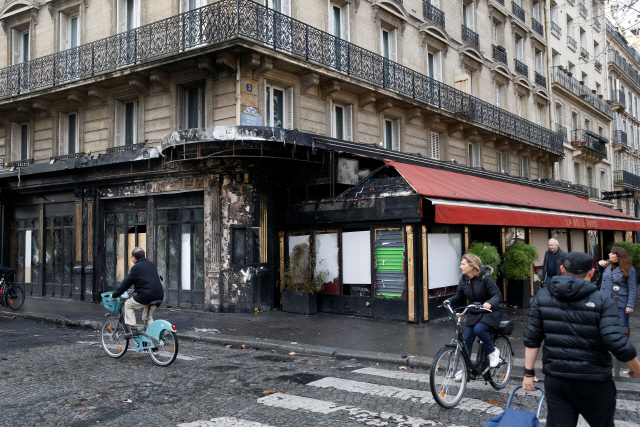 2일(현지시간) 노란조끼 시위대의 방화로 불에 탄 프랑스 파리의 한 레스토랑을 사람들이 지나가고 있다. /파리=로이터연합뉴스
