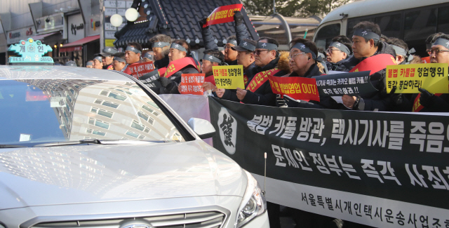 서울개인택시조합 조합원이 14일 오전 서울 더불어민주당 당사 앞에서 열린 ‘카풀 규탄 생존권 사수 결의대회’에서 카풀 앱 영업 중단을 촉구하고 있다.  /연합뉴스