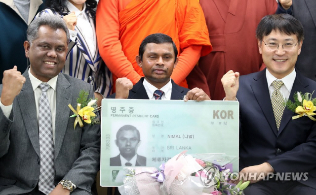 18일 오전 대구출입국관리사무소에서 열린 특별공로자 영주증 수여식에서 스리랑카 출신 이주노동자 니말씨가 영주증을 들고 기념사진을 찍고 있다./사진=연합뉴스