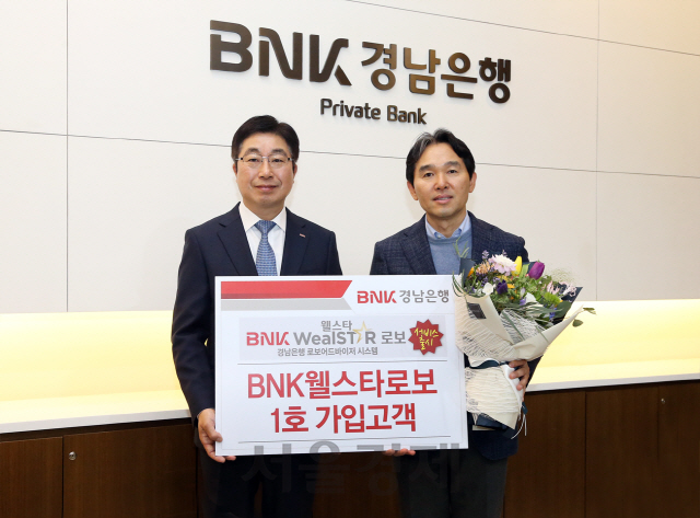 황윤철(왼쪽)BNK경남은행장이 BNK웰스타로보 1호 가입 고객에게 감사의 마음을 전하고 기념 촬영을 하고 있다. 사진제공=BNK경남은행