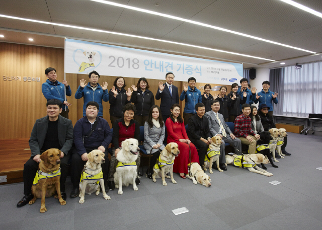 최영무(뒷줄 왼쪽 다섯번째) 삼성화재 사장이 19일 서울 서초구 삼성화재 본사에서 ‘2018 안내견 기증식’을 열고 시각장애인 14명에게 안내견을 기증한 후 안내견 훈련사들과 함께 기념사진을 찍고 있다. /사진제공=삼성화재