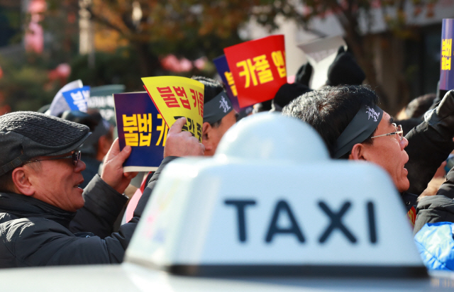 서울개인택시조합 소속 택시 운전기사들이 14일 오전 서울 여의도 더불어민주당사 앞에서 카풀 규탄 생존권 사수 결의대회를 열고 있다. 택시 단체들은 20일 여의도에서 대규모 시위를 예고했다. / 연합뉴스