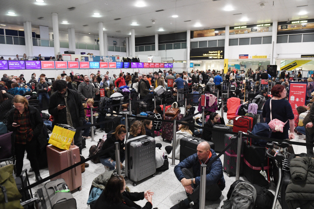 20일(현지시간) 영국 런던 인근의 개트윅 국제공항에서 드론 출현으로 항공기 이착륙이 금지되자 수많은 승객들이 바닥에 앉은 채 비행 재개를 기다리고 있다./런던=EPA연합뉴스