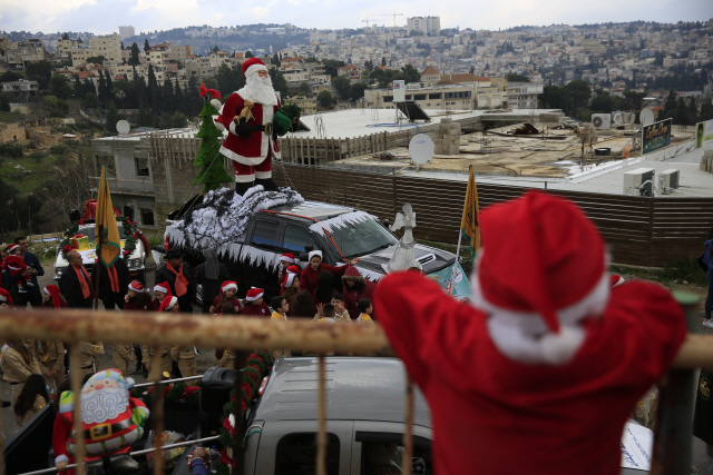 24일 중동 분쟁의 중심인 이스라엘 나사렛에서 산타클로스 복장을 한 아이가 연례 크리스마스 퍼레이드를 지켜보고 있다. /나사렛=AP연합뉴스