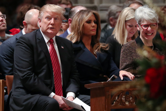 도널드 트럼프(왼쪽) 미국 대통령이 24일(현지시간) 부인 멜라니아(가운데) 여사와 함께 워싱턴 국립대성당에서 열린 미사에 참석해 앉아 있다. /로이터연합뉴스