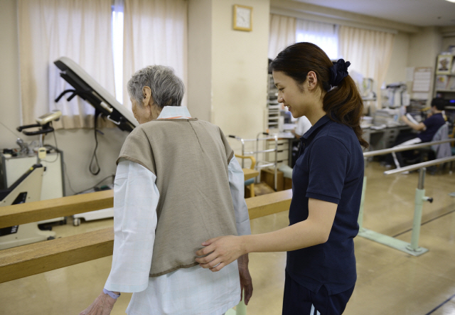 도쿄 병원에서 치료사가 고령 환자의 이동을 돕고 있다. /블룸버그