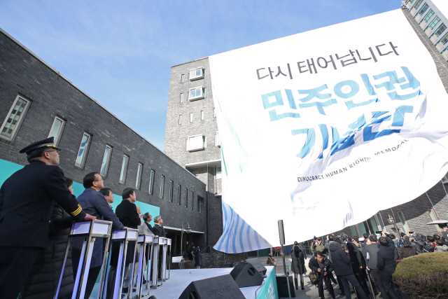 이낙연 국무총리와 정부측 인사들이 26일 서울 용산구 경찰청인권센터 정문에서 고문피해자와 희생자 유가족, 일반 시민 등 입장하는 시민을 직접 맞이하는 환영식을 하며 본관 건물 전체를 현수막으로 덮는 버튼을 누르고 있다. /연합뉴스