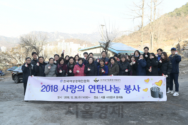 26일 ‘2018 사랑의 연탄나눔 봉사’에 참여한 한무경(왼쪽에서 일곱번째) 한국여성경제인협회 회장을 포함한 임직원 등이 손가락하트를 만들어보이고 있다. /사진제공=한국여성경제인협회