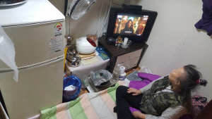 26일 서울 영등포구 쪽방촌에 거주하는 신금자(62)씨가 전기장판조차 없는 방에서 텔레비전을 보고 있다.   /서종갑기자