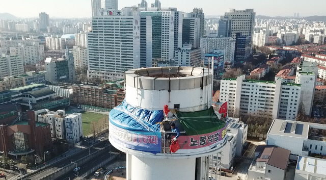 24일 오전 서울 양천구 열병합발전소 굴뚝에서 금속노조 충남지부 파인텍지회 홍기탁 전 지회장과 함께 굴뚝 농성을 벌이는 박준호 사무장이 아침 식사를 마친 뒤 용기가 담긴 가방을 줄에 메달아 동료들에게 전달하고 있다. /연합뉴스TV=연합뉴스