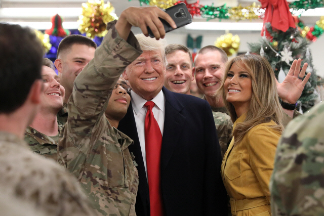 도널드 트럼프 미국 대통령이 26일(현지시간) 부인 멜라니아 여사와 이라크 바그다드 서쪽 알아사드 공군기지를 ‘깜짝’ 방문해 미군 장병들과 셀카를 찍고 있다.    /바그다드=로이터연합뉴스