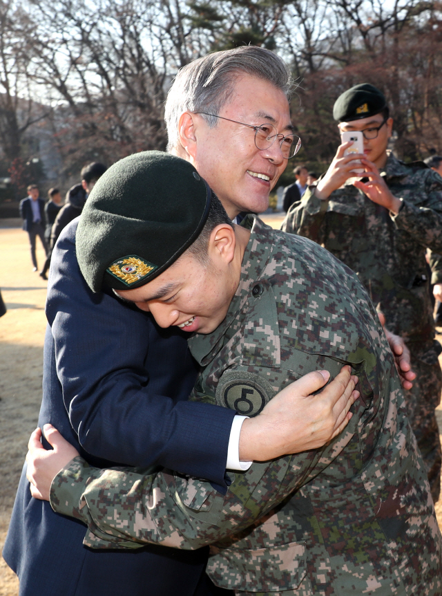 문재인 대통령이 지난 19일 오후 청와대 녹지원에서 남북 공동 유해발굴지역 지뢰 제거 및 도로 개설 작전을 수행한 화살머리고지 장병들을 격려하며 포옹하고 있다. /연합뉴스