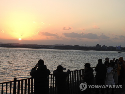 지난해 마지막 날인 12월 31일 충남 당진 신평면 행담도 휴게소를 찾은 시민들이 서산으로 넘어가는 해를 바라보는 모습./연합뉴스