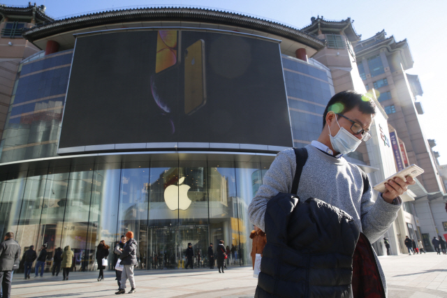 마스크를 쓴 한 남성 뒤로 중국 베이징의 애플 매장이 신형 ‘아이폰XR’을 홍보 중이다. /베이징=EPA연합뉴스