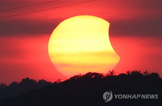 지난해 8월 11일 오후 서울 마포구 가양대교 너머로 붉은 해가 달에 일부 가려지는 부분일식이 진행되고 있다./연합뉴스