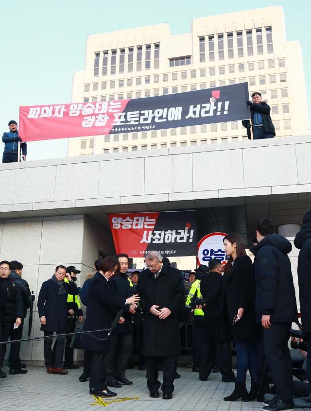 양승태 전 대법원장이 11일 오전 서울 서초동 대법원 앞에서 사법행정권 남용 의혹 관련 피의자 신분으로 검찰에 출석하기 전 입장을 밝히기 위해 자리를 잡고 있다. 양 전 대법원장 뒤로 법원노조 조합원들이 펼침막과 손팻말을 든 채 양 전 대법원장을 규탄하고 있다. /연합뉴스