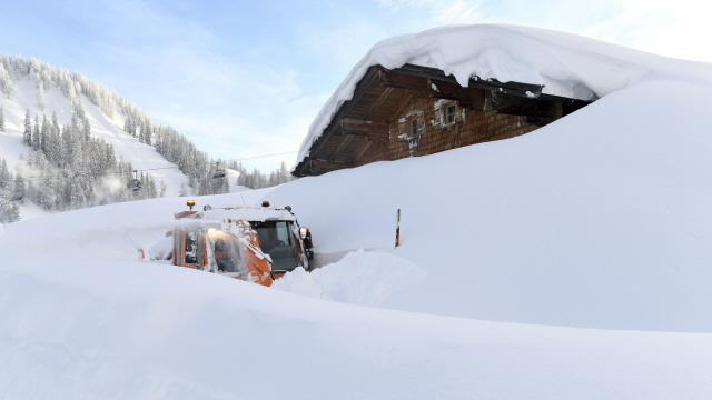 오스트리아 잘츠부르크주의 한 마을에 폭설이 내려 눈이 집 지붕까지 쌓인 가운데 11일(현지시간) 제설차가 눈을 치우고 있다./잘츠부르크=AP연합뉴스