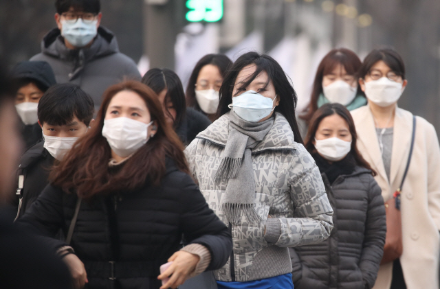 고농도 미세먼지가 기승을 부리면서 수도권을 포함한 전국 곳곳에 미세먼지 비상저감조치가 시행된 14일 오전 서울 광화문 네거리에서 출근길에 오른 시민들이 마스크를 쓰고서 횡단보도를 건너고 있다./연합뉴스