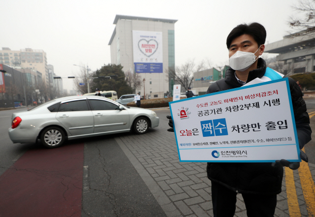 고농도 미세먼지가 기승을 부려 수도권 지역에 미세먼지 비상저감조치가 시행된 14일 오전 인천시 남동구 인천시청 정문에서 시청 직원들이 차량 2부제 시행을 알리는 알림판을 들고 있다. /연합뉴스