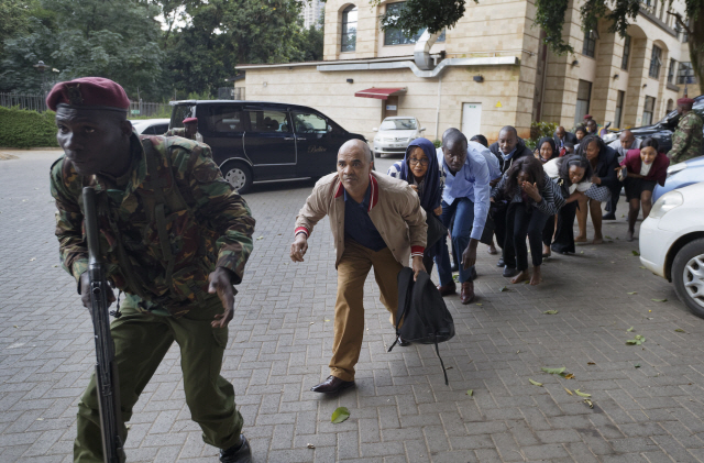 케냐 수도 나이로비 도심 상업단지 인근에서 15일(현지시간) 최소 15명이 숨지는 총격과 폭탄 테러가 발생한 직후 시민들이 경찰의 뒤를 따라 안전한 곳으로 피신하고 있다./AP=연합뉴스