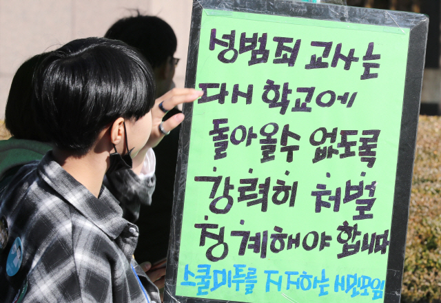 지난해 11월 서울 파이낸스 빌딩 앞에서 열린 ‘여학생을 위한 학교는 없다’ 스쿨미투 집회에서 참가자들이 성범죄 교사 처벌을 요구하는 플래카드를 보고 있다./연합뉴스