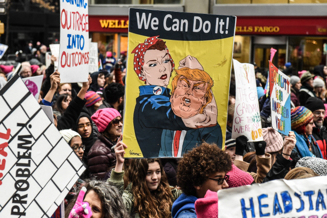 3년째 이어지고 있는 ‘여성행진 시위’에 참여한 한 여성이 19일(현지시간) 도널드 트럼프 대통령을 제압하는 장면이 담긴 그림을 들고 있다. /뉴욕=AFP연합뉴스