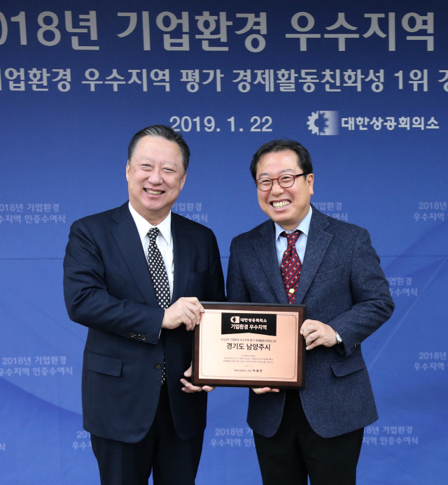 22일 경기도 남양주시청에서 열린 ‘2018년 기업환경 우수지역 인증수여식’에서 박용만(왼쪽) 대한상공회의소 회장이 조광한 남양주시장에게 인증현판을 전달한 후 기념촬영을 하고 있다. /사진제공=대한상공회의소