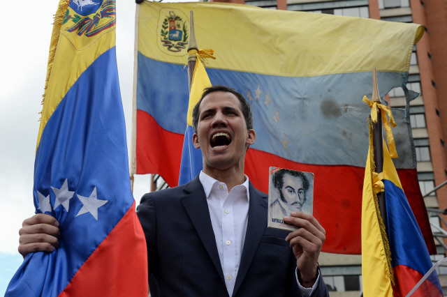 후안 과이도(35) 베네수엘라 국회의장이 23일(현지시간) 수도 카라카스에서 열린 대규모 반정부 집회에서 헌법전을 손에 들고 자신을 ‘임시 대통령’으로 선언하고 있다. /카라카스=AFP연합뉴스