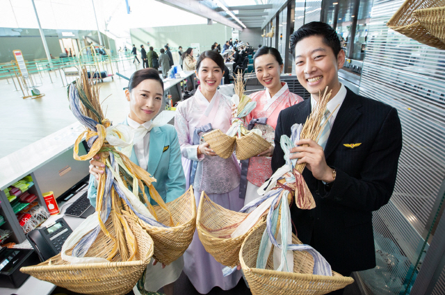 대한항공 객실승무원들과 승객들이 인천공항 제2 여객터미널 대한항공 카운터에서 새해를 맞아 고객들의 행운과 안전을 기원하는 복조리를 걸고 기념촬영을 하고 있다. 대한항공은 황금 돼지의 해를 맞아 28일부터 2월 10일까지 국내 사업장에 복조리를 거는 행사를 진행한다./사진제공=대한항공