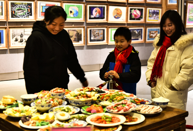 지난 1월 25일 안휘성 허페이의 한 갤러리에 전시된 춘제 음식 ‘녠예판’을 방문객들이 살펴보고 있다. 춘제 전날 저녁 가족들이 모여 앉아 이런 음식을 먹으며 ‘신년’를 맞는다. /신화연합뉴스