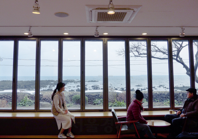 카페 ‘서연의 집’을 찾은 방문객이 감상에 젖은 듯 유리창 너머 바다 풍경을 바라보고 있다.