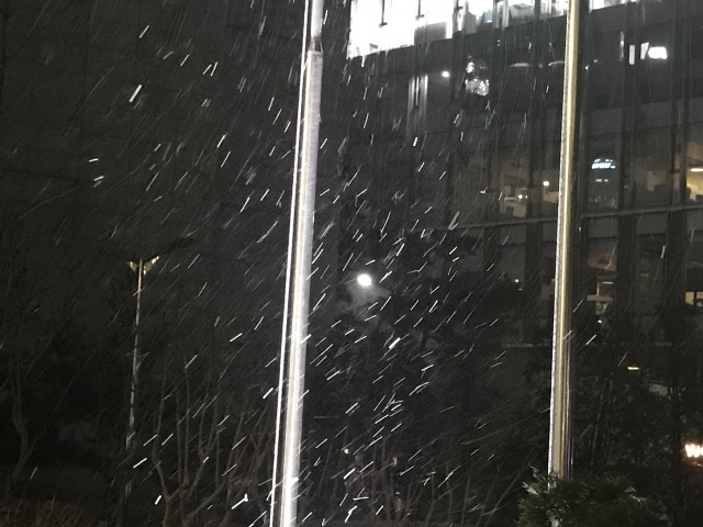 설 연휴가 끝나고 첫 출근길인 7일 오전 6시23분께 서울 광화문 한 빌딩 앞에 눈이 내리고 있다. 건너편 빌딩 한 층에는 이미 불이 환하게 켜져 있다./연합뉴스