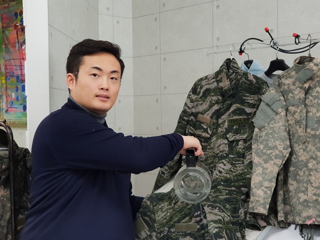 티에프제이글로벌 진의규 대표가 군복에 물을 부어 보이며 ‘초발수 전투복’에 대해 설명하고 있다.