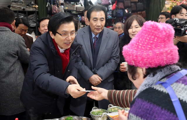 황교안(왼쪽) 전 국무총리가 8일 오전 대구 서문시장을 방문해 떡볶이 값을 지불하고 있다. /연합뉴스