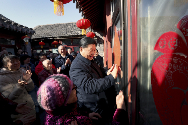 시진핑(가운데) 중국 국가주석이 최대 명절인 춘제(春節·중국의 설)를 앞두고 1일 베이징 첸먼 인근의 ‘후퉁’(좁은 골목의 옛 서민 주택가)을 방문해 주민들과 함께 춘제 장식물을 붙이고 있다./AP연합뉴스