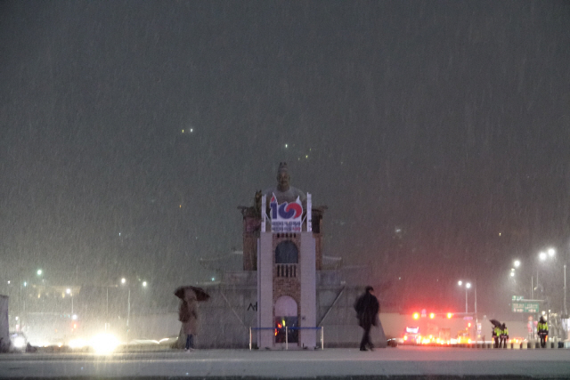 눈이 내리는 15일 이른 아침 시민들이 서울시 종로구 광화문광장 세종대왕상 앞을 지나고 있다. /연합뉴스