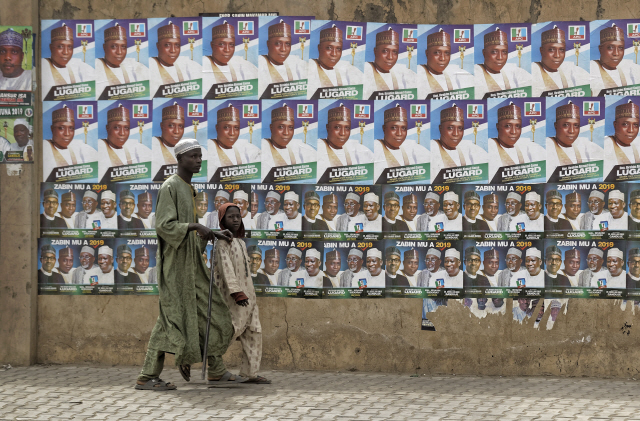 16일(현지시간) 나이지리아 북부 카노주에서 주민들이 대선 후보 포스터가 붙은 거리를 지나고 있다. /카노=AP연합뉴스