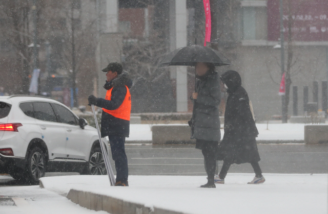 서울과 수도권 지역에 눈이 내리는 15일 오전 서울 종로구 정부서울청사 앞에서 출근길 시민들이 발걸음을 옮기고 있다./연합뉴스