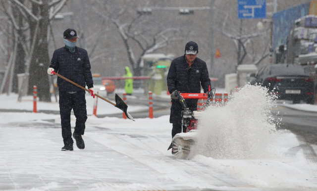 서울과 수도권 지역에 눈이 내리는 15일 오전 서울 영등포구 여의도 국회에서 시설관계자들이 쌓인 눈을 치우고 있다./연합뉴스