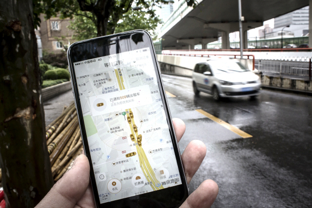 중국 상하이의 한 시민이 택시호출앱 디디추싱으로 택시를 부르고 있다. 디디추싱은 모바일결제가 확산되는데 결정적인 역할을 했다. /블룸버그