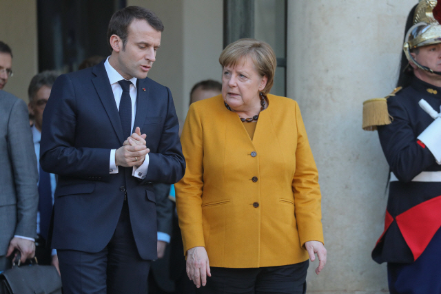 에마뉘엘 마크롱(왼쪽) 프랑스 대통령과 앙겔라 메르켈 독일 총리가 27일(현지시간) 파리 엘리제궁에서 정상회담을 한 뒤 대화를 나누며 걸어나오고 있다. /파리=AFP연합뉴스