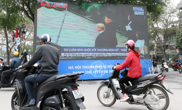 2차 북미정상회담이 열린 28일 오토바이를 탄 하노이 시민들이 오페라하우스 앞에 설치된 전광판 앞을 지나가고 있다./연합뉴스