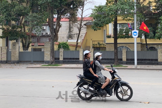 1일 오후 북한 인공기와 베트남 금성홍기가 펄럭이는 가운데 하노이 여성들이 오토바이를 타고 가고 있다./하노이=정영현기자