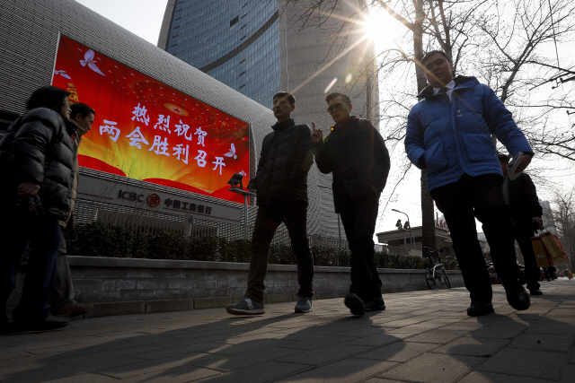 3월 1일 베이징 시내 한 건물에 걸린 ‘양회 개최를 축하한다’는 스크린 앞으로 시민들이 지나가고 있다. /AP연합뉴스