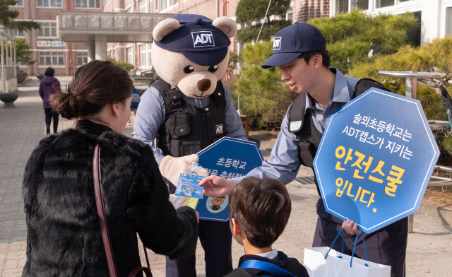 ADT캡스 요원이 4일 경기도 의정부 솔뫼초등학교에서 학부모와 학생에게 호루라기와 범죄 안전 가이드 책자를 나눠주고 있다. /사진제공=ADT캡스