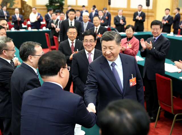 시진핑 중국 국가주석이 지난 7일(현지시간) 13기 전국인민대표대회(전인대)가 열리고 있는 베이징 인민대회당에서 간쑤성 대표자들과 인사를 나누고 있다.   /베이징=신화연합뉴스