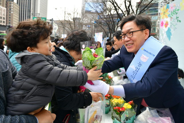 지난 14일 서울 광화문 일대에서 진행된 ‘새봄맞이 고객사랑 가두캠페인’에서 이대훈(오른쪽) 농협은행장이 어린이에게 화분을 건네고 있다./사진제공=농협은행