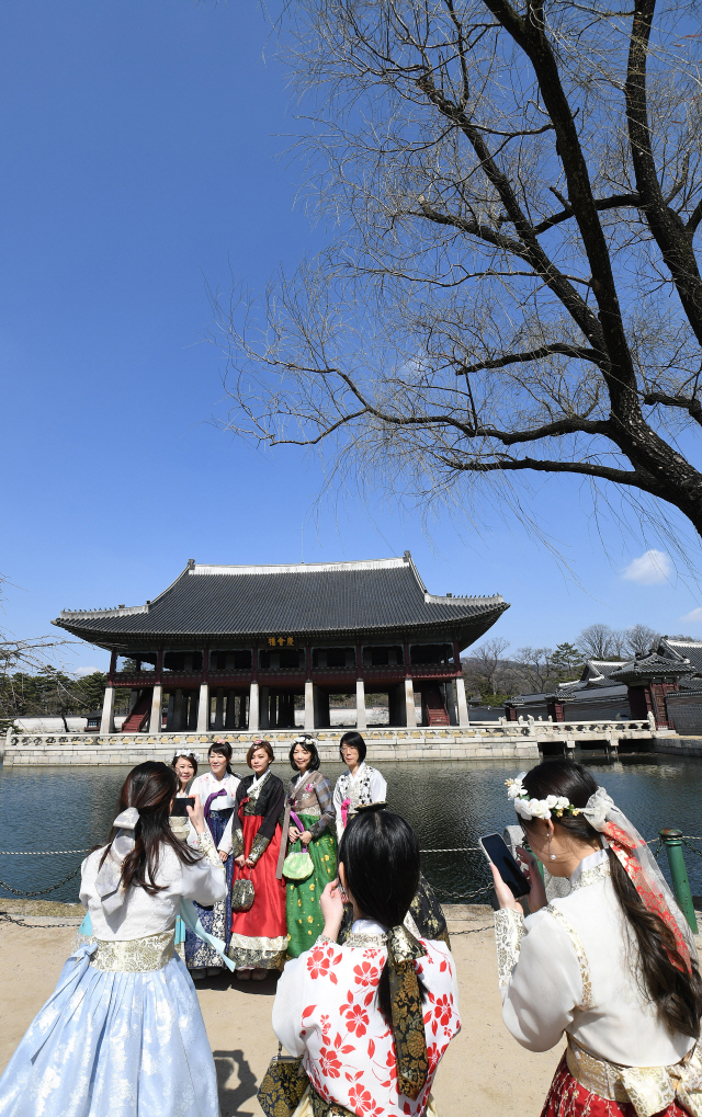 나들이객들이 17일 서울 경복궁을 찾아 경회루를 배경으로 사진을 찍으며 포근한 봄날씨를 만끽하고 있다. 이날 전국적으로 미세먼지 수치가 ‘보통’ 수준으로 나타나 맑은 하늘을 즐기려는 시민들로 관광지가 크게 북적였다. /오승현기자